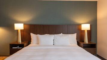 A hotel room with a large bed, two bedside tables, and a headboard with vertical slats.