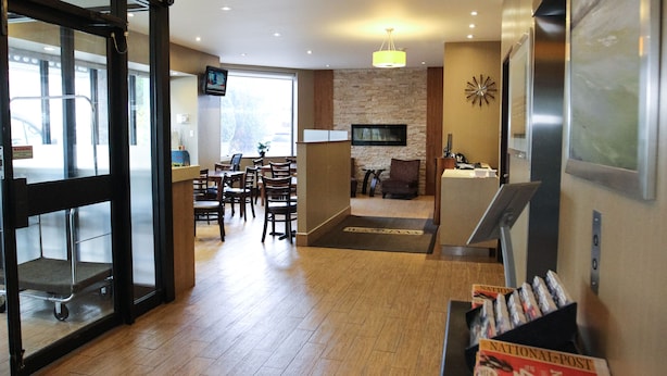 A hotel lobby with a reception desk, seating area, and a fireplace. - Welcominns Hotel Ottawa (Ottawa)