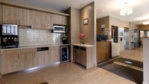 A modern kitchen with wooden cabinets, a microwave, and a built-in espresso machine. - Welcominns Hotel Ottawa (Ottawa)