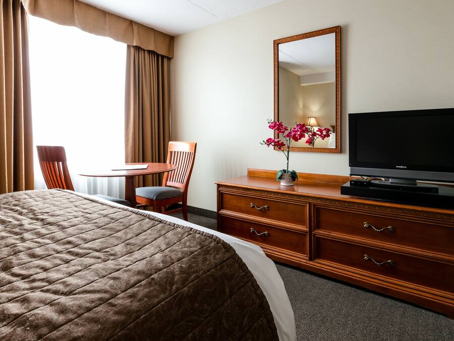 Une chambre d’hôtel équipée d’un lit, d’un bureau, d’une chaise, d’une commode, d’une télévision et d’un miroir.