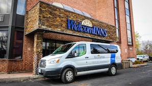 A white van parked in front of a building with a 'Welcome Inn' sign. - Welcominns Hotel Ottawa (Ottawa)