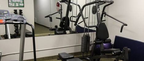 A gym with a treadmill, bench press, and various exercise machines.