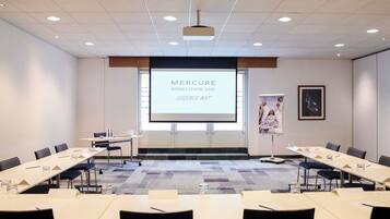 A conference room with a large screen displaying 'MERCURE RENNES CENTRE GARE DEGEMER MAT'.