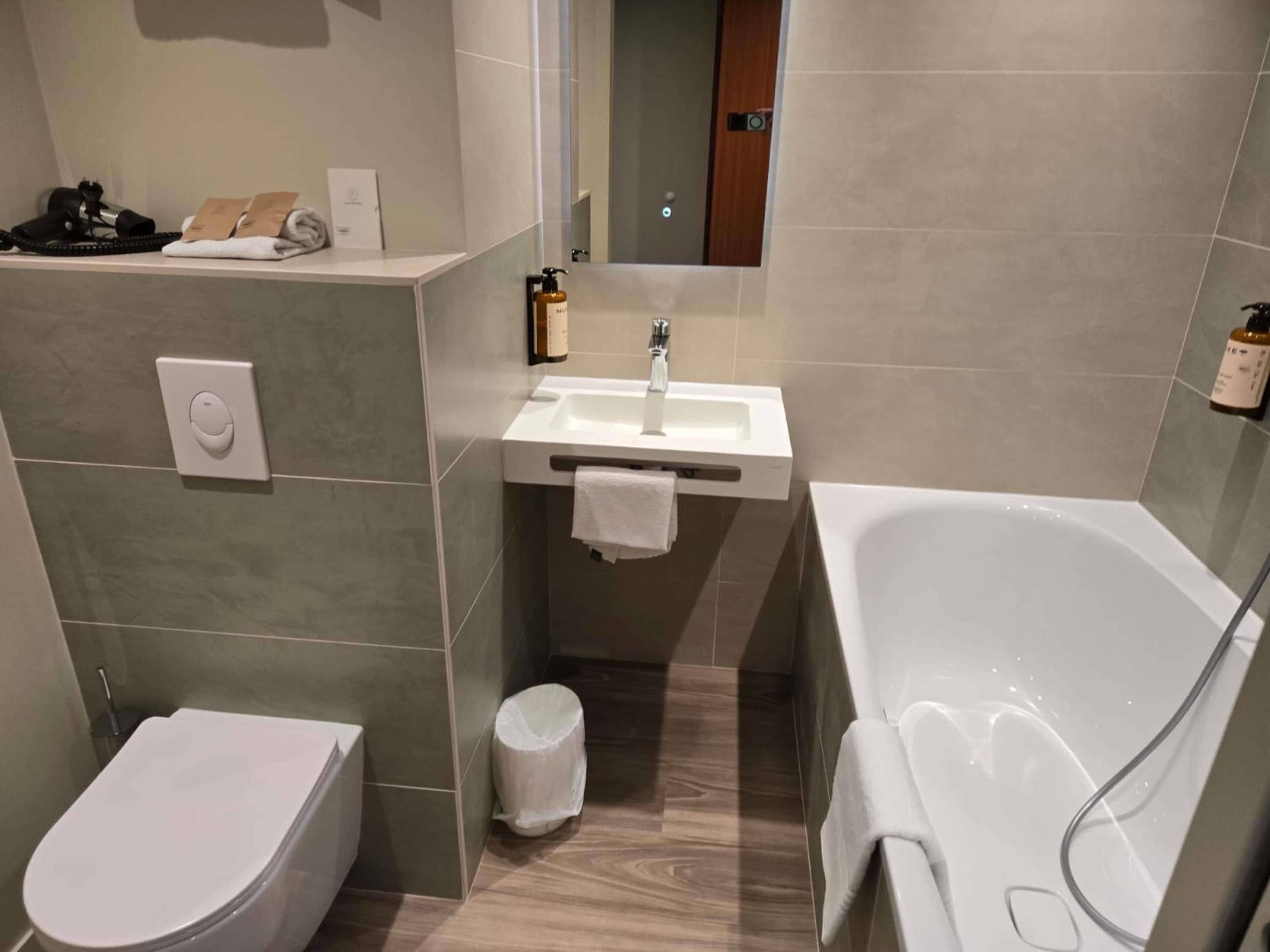 A modern bathroom with a toilet, sink, and bathtub.