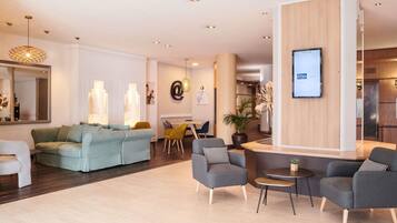 Un salon moderne comprenant un canapé, des fauteuils, une table basse et un coin repas.