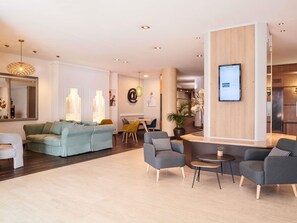 En moderne stue med sofa, lænestole, sofabord og et spiseområde.