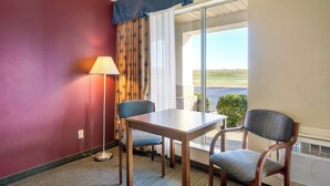 A hotel room with a table and two chairs, a lamp, and a large window with a view of the outdoors. - Red Roof Inn Vincennes (Vincennes)
