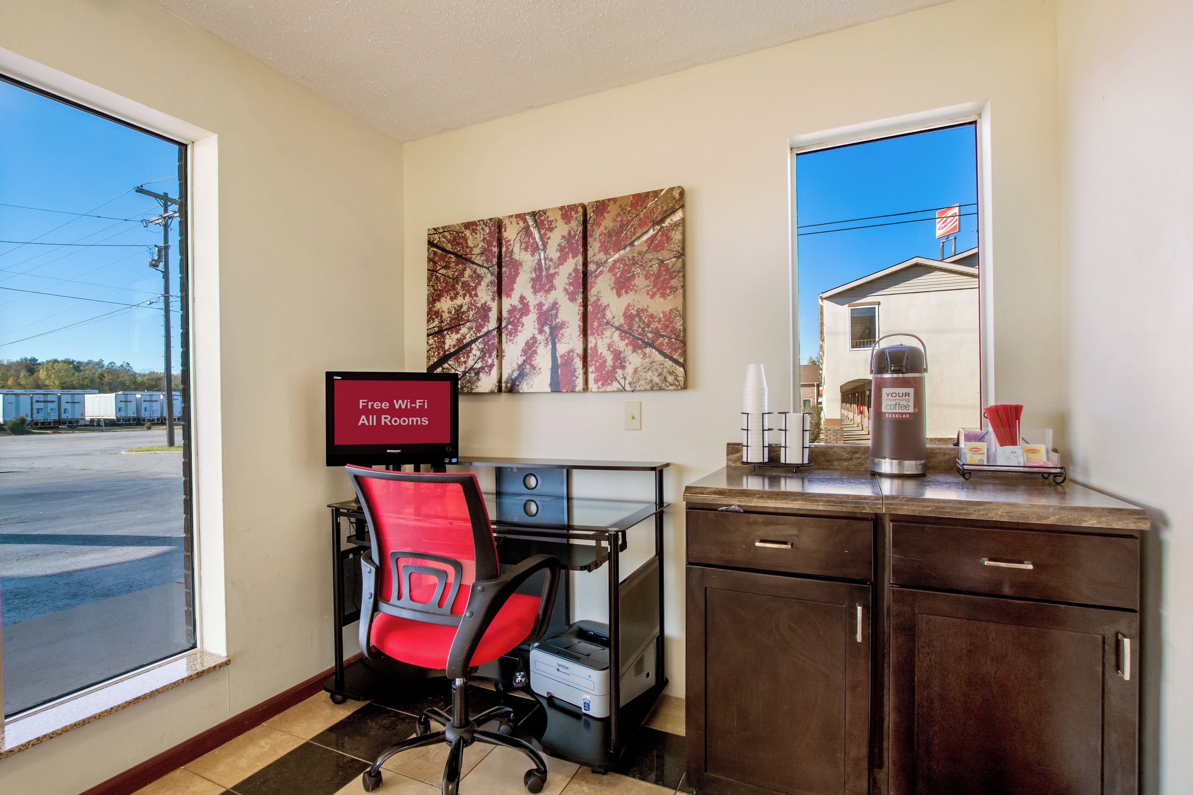 A hotel room with a desk, chair, and a coffee station.
