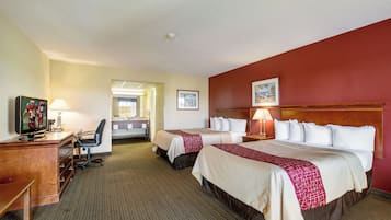 Habitación de hotel con dos camas, un escritorio, una silla y un televisor.