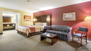 A hotel room with a bed, sofa, armchair, and a small table. - Red Roof Inn Vincennes (Vincennes)