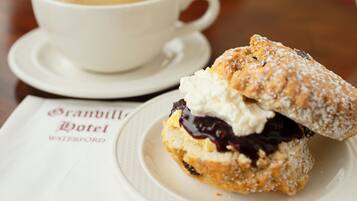 Sobremesa com chantilly e compota de frutos vermelhos num prato, acompanhada por uma chávena de café num pires.