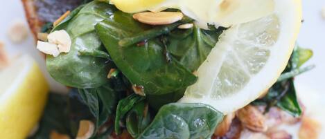 A dish with fish, spinach, lemon, and a creamy sauce.