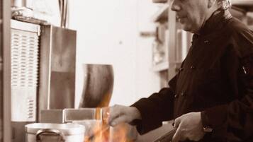 A chef cooking with a pan on a stove in a kitchen.