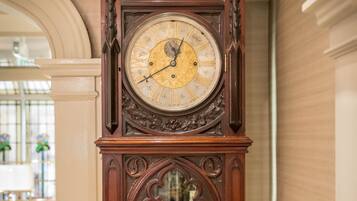 A large, ornate grandfather clock with a glass door and a brass key.