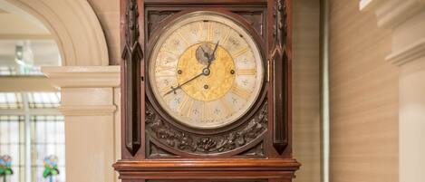 A large, ornate grandfather clock with a glass door and a brass key.