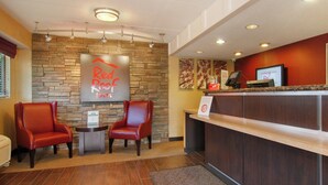 A reception area with a stone wall, two red chairs, a reception desk, and a Red Roof sign.