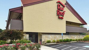 A Red Roof Inn with a stone facade, a parking lot, and a clear sky.