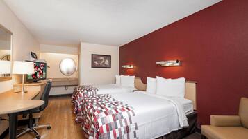 Quarto de hotel com cama, escrivaninha, cadeira e televisão.