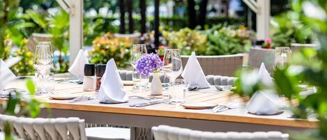 An outdoor dining area with neatly set tables, white napkins, and clear glassware.