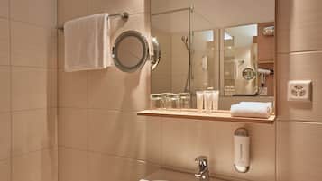 Un baño moderno con lavamanos, espejo, toallero y repisas con artículos de aseo.