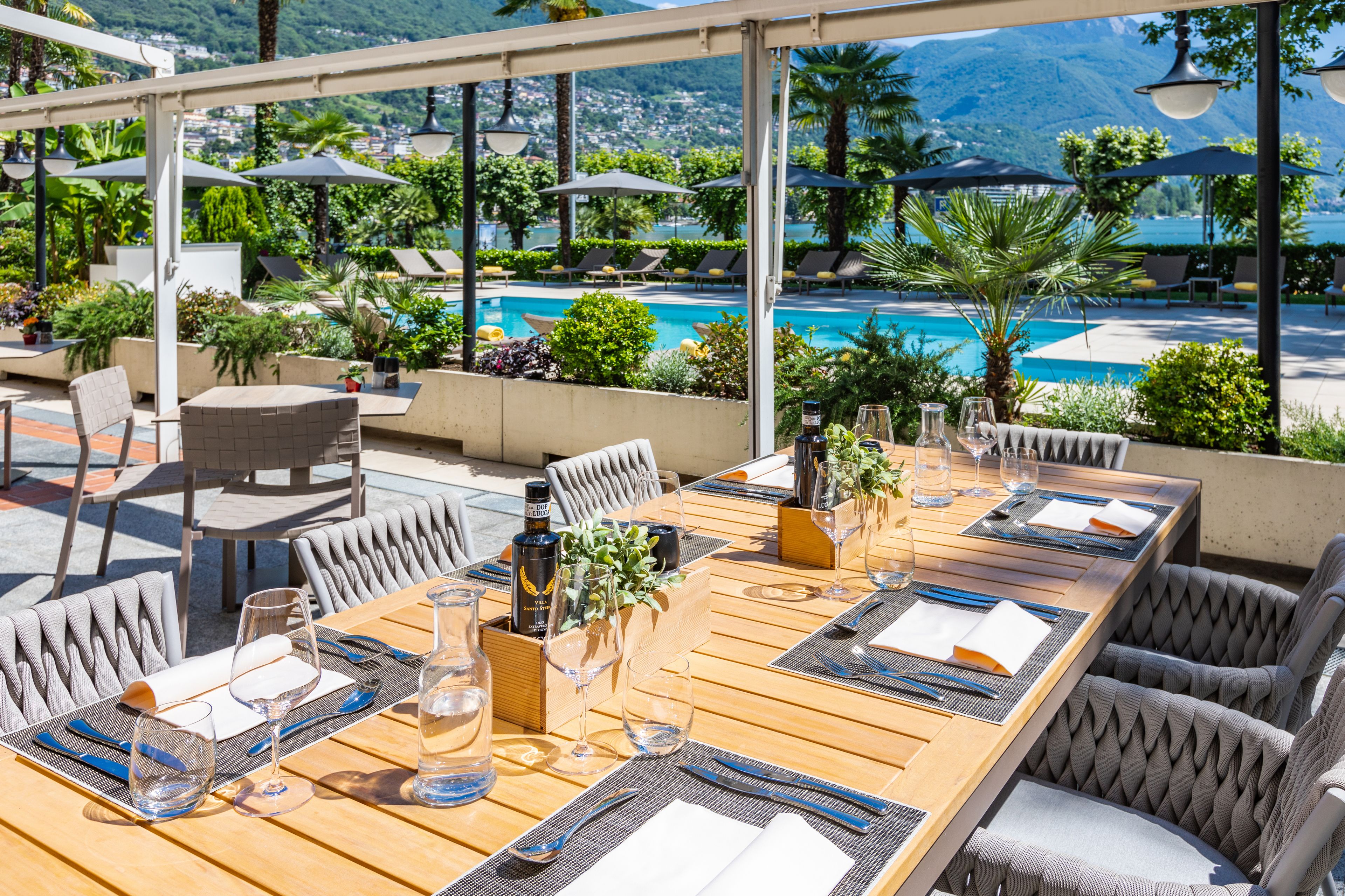 Un espace extérieur aménagé pour prendre les repas, avec vue sur une piscine et des montagnes.