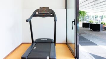 Una cinta de correr en una habitación con una puerta de cristal que da a un espacio exterior.