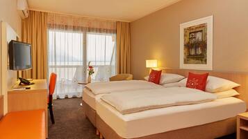 Une chambre d’hôtel comprenant un lit, un bureau avec une télévision, une chaise et une lampe.