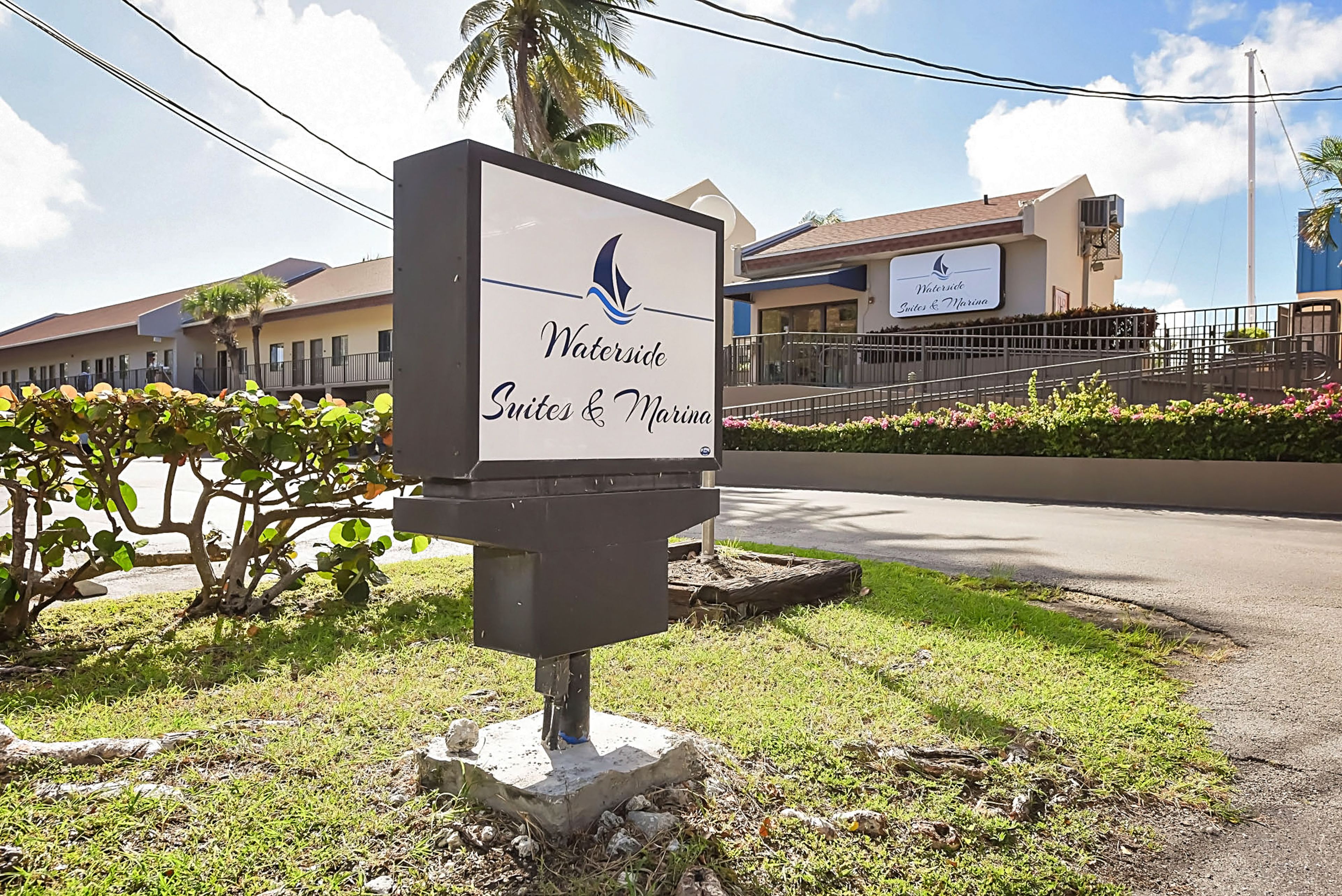 A sign for Waterside Suites & Marina with a clear view of the building in the background.