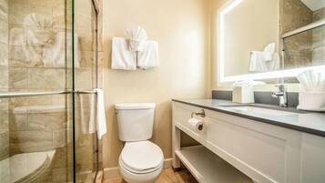 Un bagno moderno con cabina doccia in vetro, un water, un lavandino con specchio e asciugamani a parete.