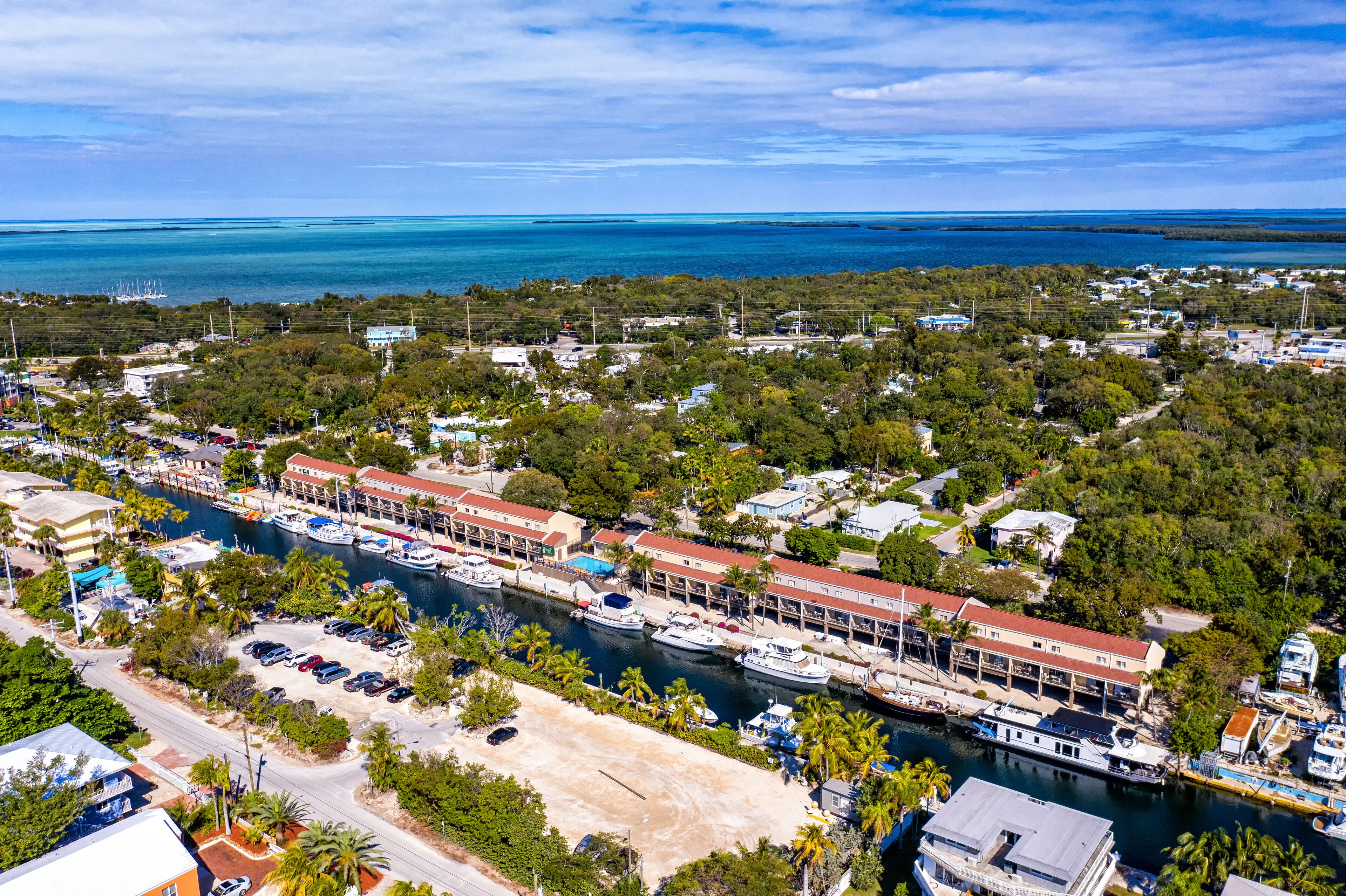 An aerial view of a coastal town with a marina, boats, and a mix of residential and commercial buildings.