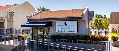 A hotel named "Waterude Suites & Marina" with a clear entrance, outdoor seating, and a view of the marina.