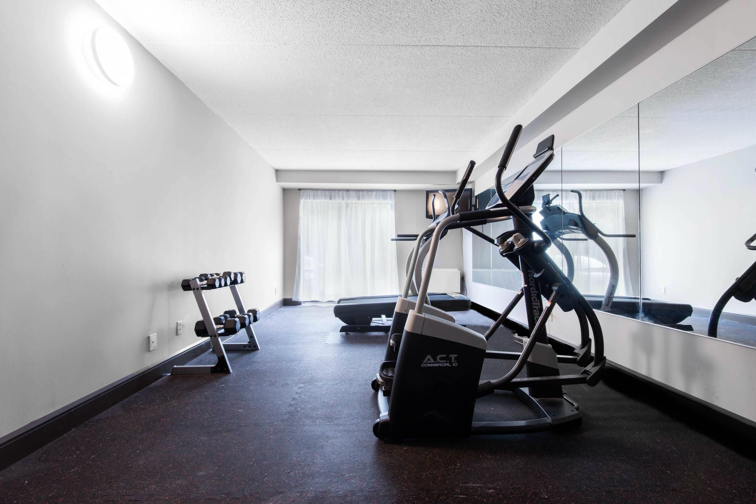 A gym with treadmills, a stationary bike, and dumbbells.