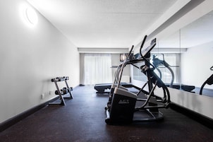 Un gimnasio con cintas de correr, una bicicleta estática y mancuernas.