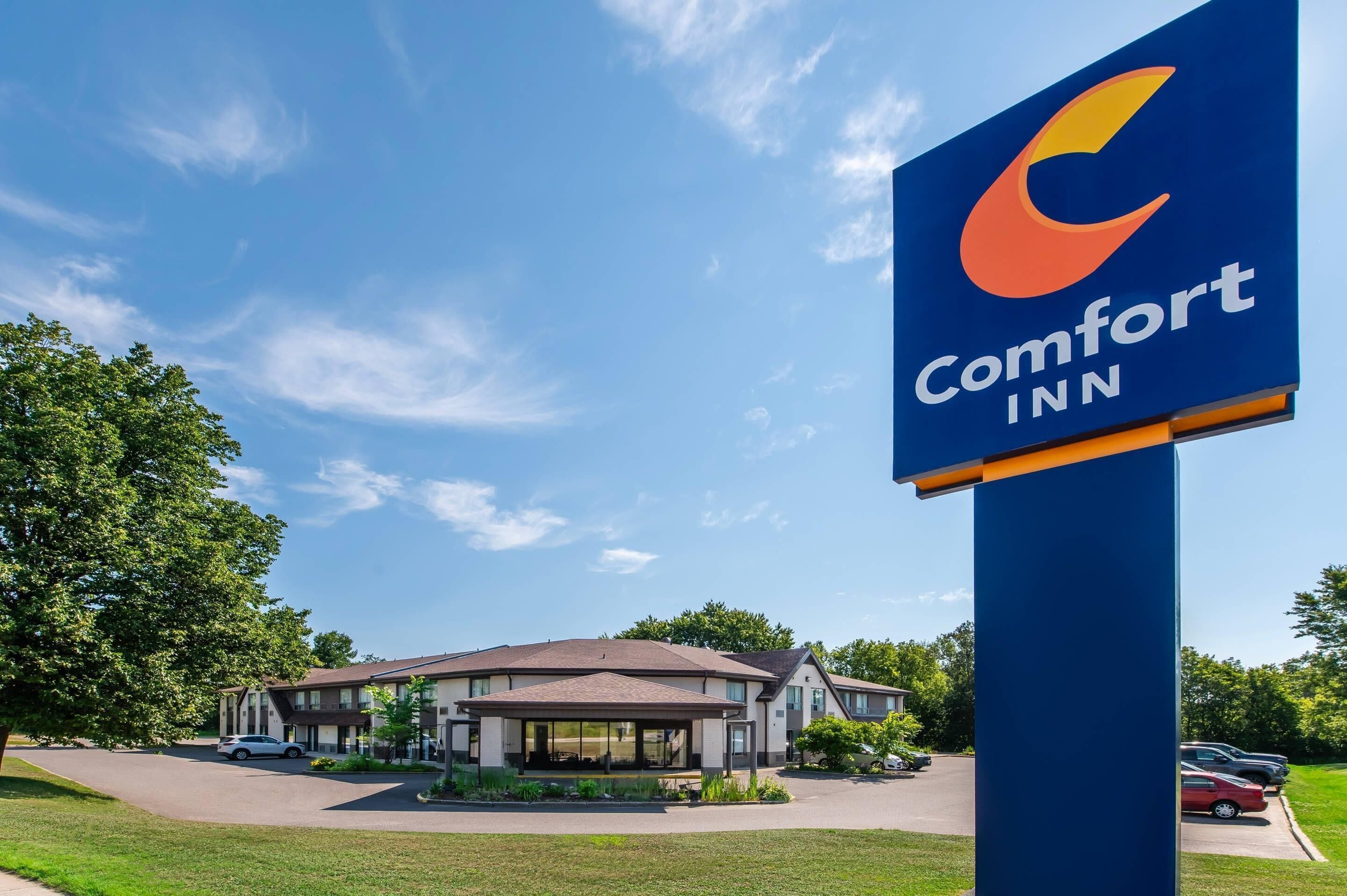 A Comfort Inn hotel with a clear blue sky, a large sign, and a parking lot.