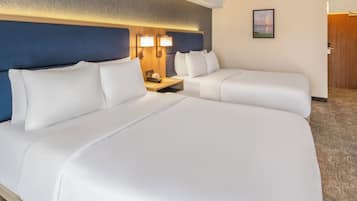 A hotel room with two beds, a nightstand, a clock, and a framed picture on the wall.
