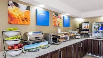 Een ontbijtbuffet met diverse eetmogelijkheden, zoals fruit, wafels en gebak.