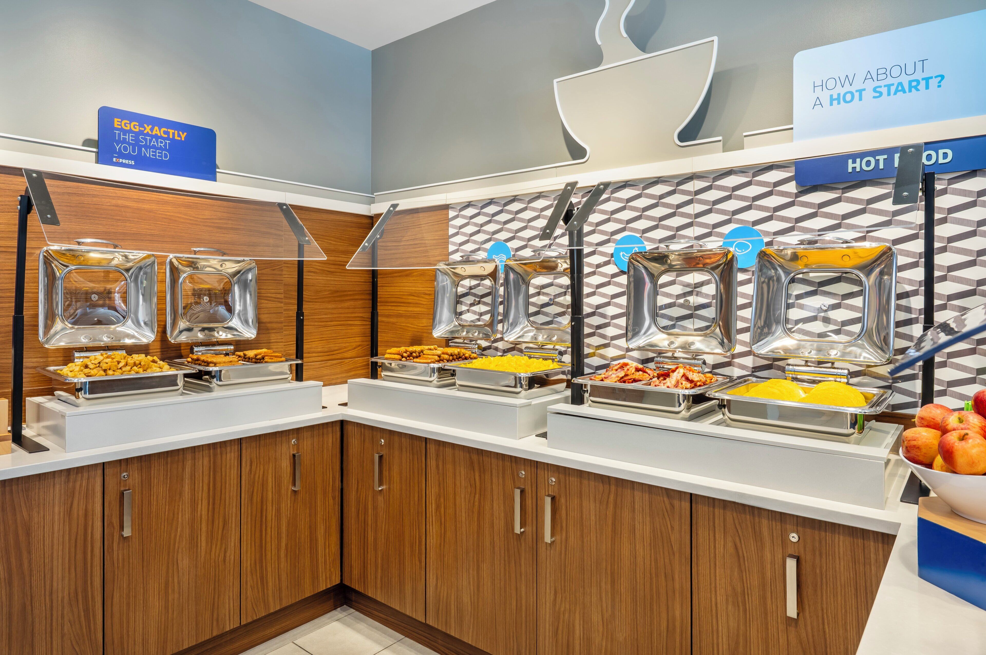 A buffet setup with multiple food dispensers and a sign indicating a hot start.