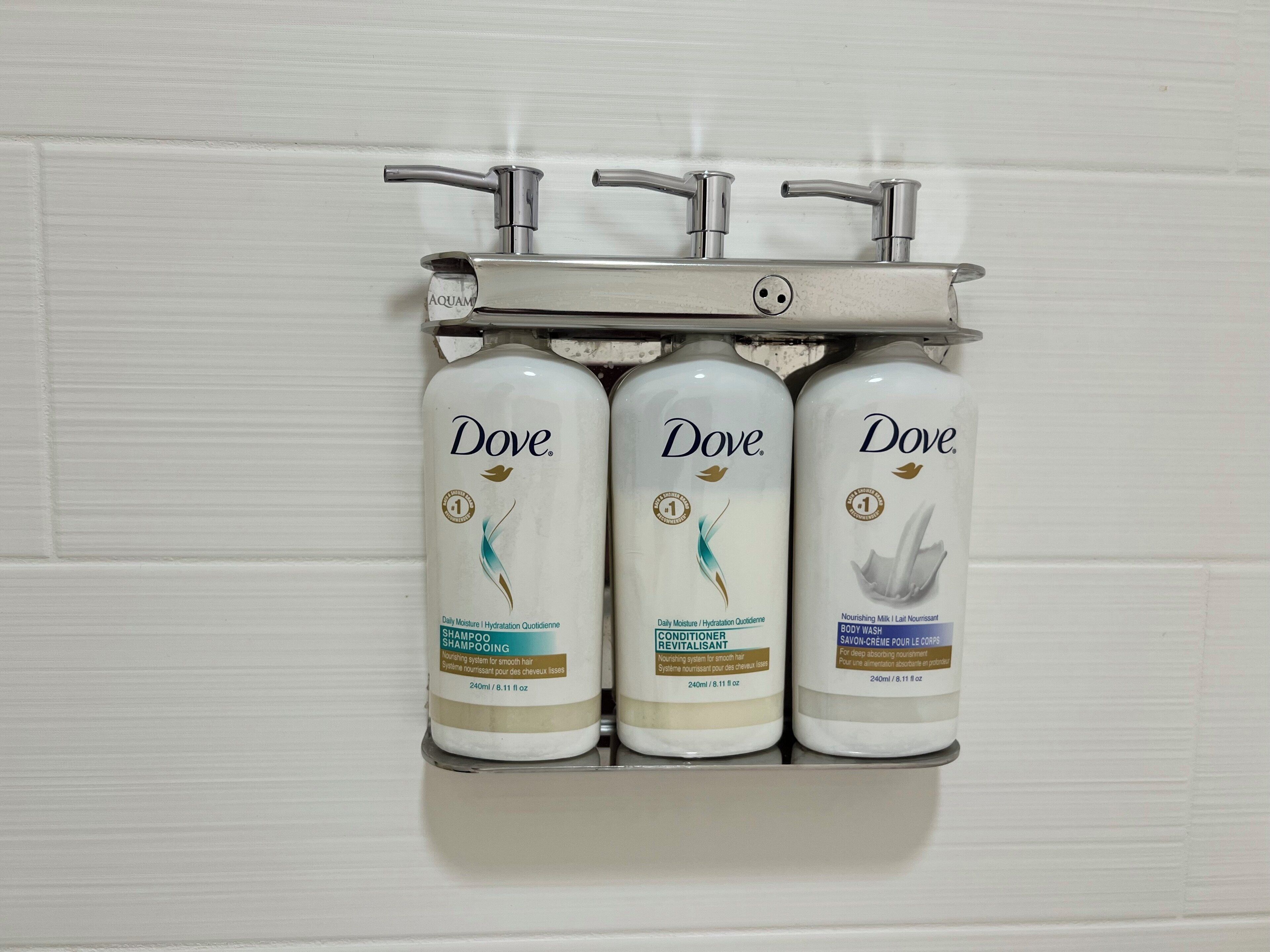 Drei Dove-Shampooflaschen in einem Wandhalterung.