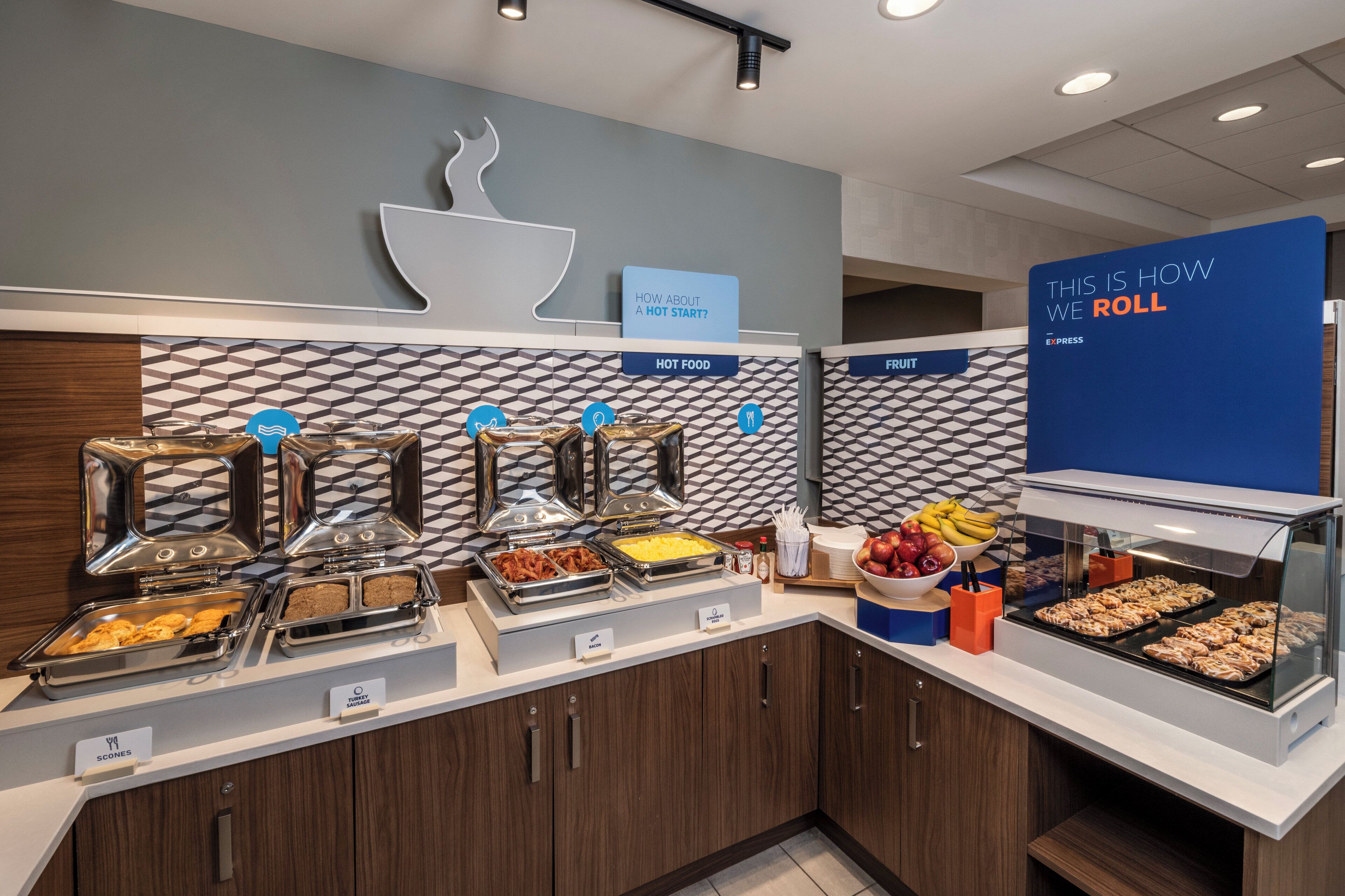 A buffet with labeled food stations including hot food, fruit, and bacon.