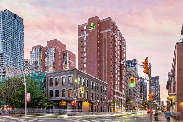 A hotel with a brick facade, multiple floors, and a sign indicating it's a Holiday Inn Express.