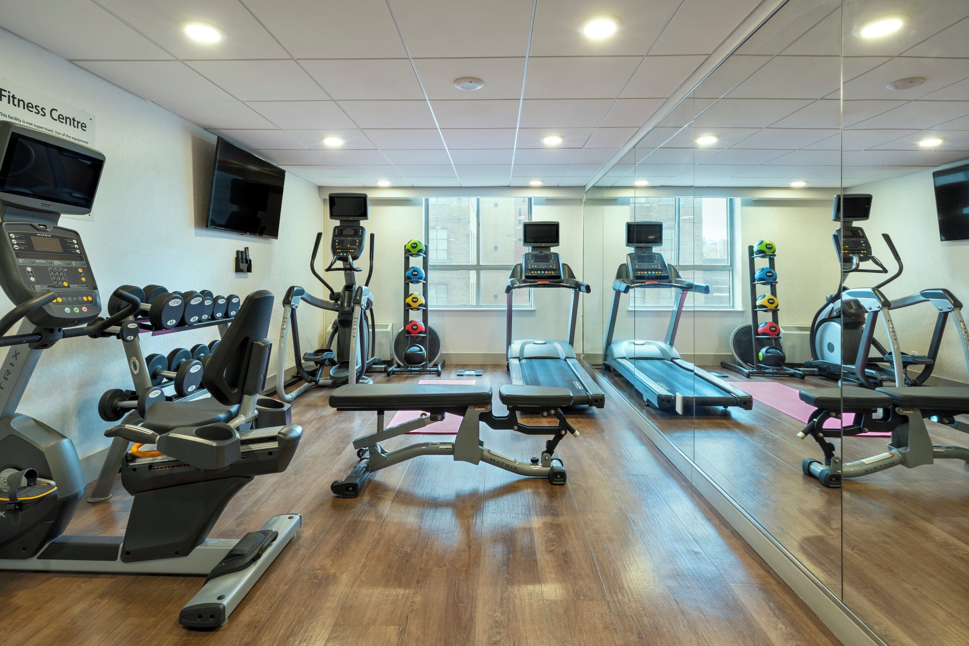 Un gimnasio equipado con cintas de correr, máquinas de pesas y un espejo grande.