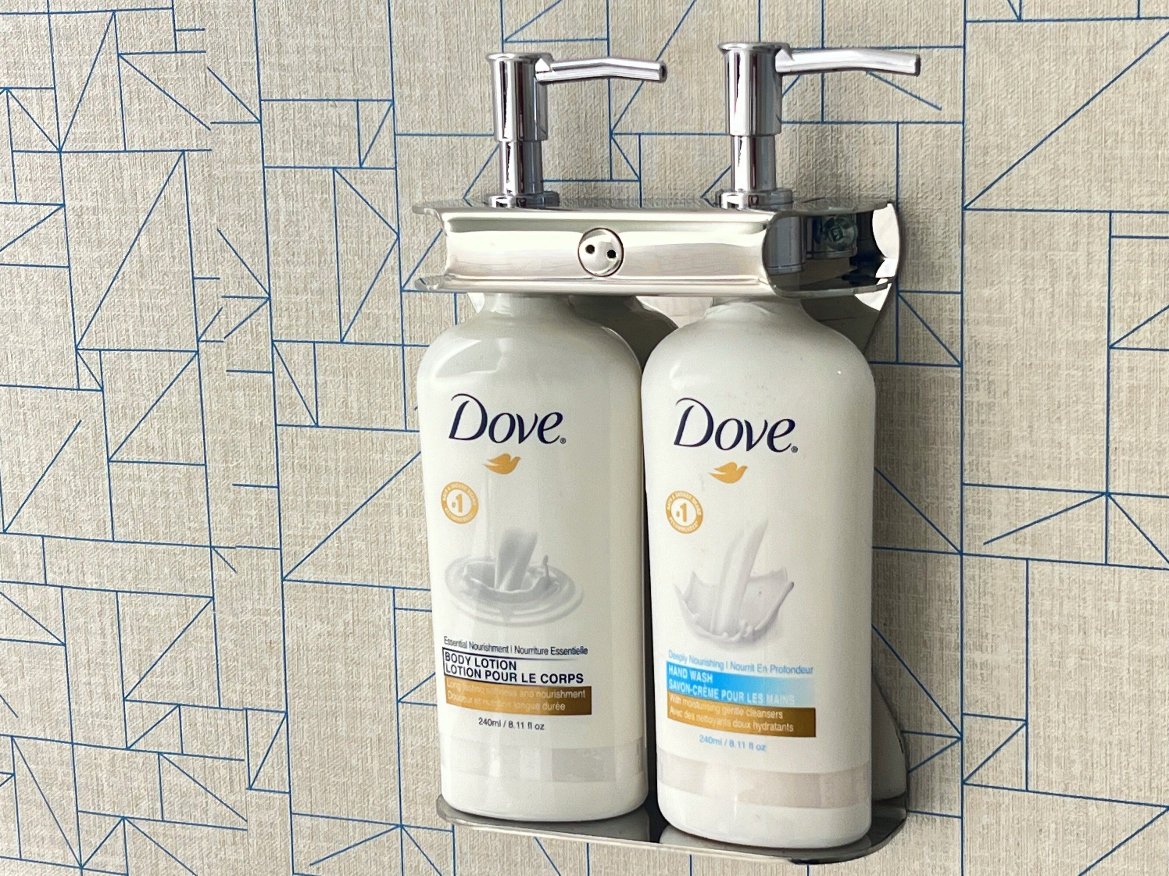 Two Dove body lotion bottles mounted on a wall with a geometric tile pattern.