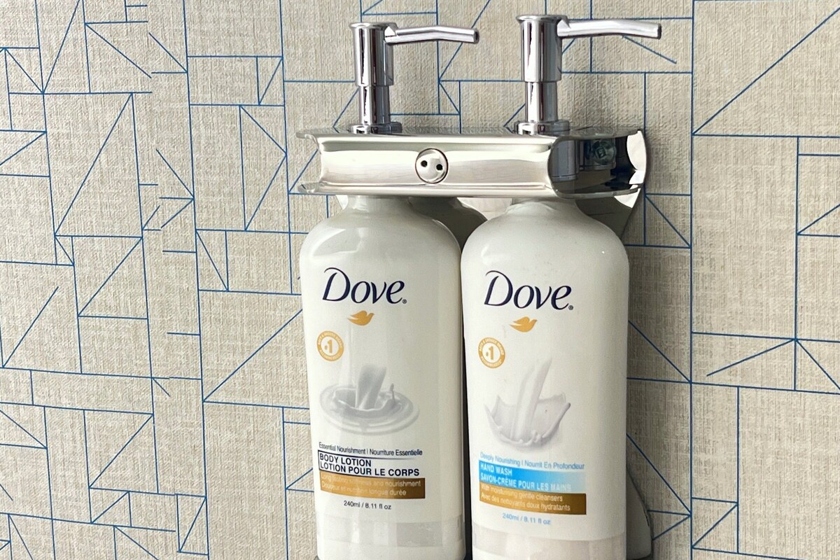 Two Dove body lotion bottles mounted on a wall with a geometric tile pattern.