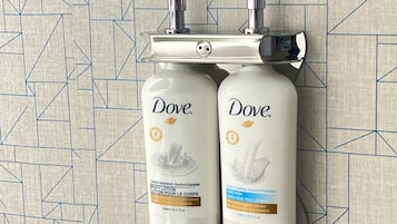 Two Dove body lotion bottles mounted on a wall with a geometric tile pattern.