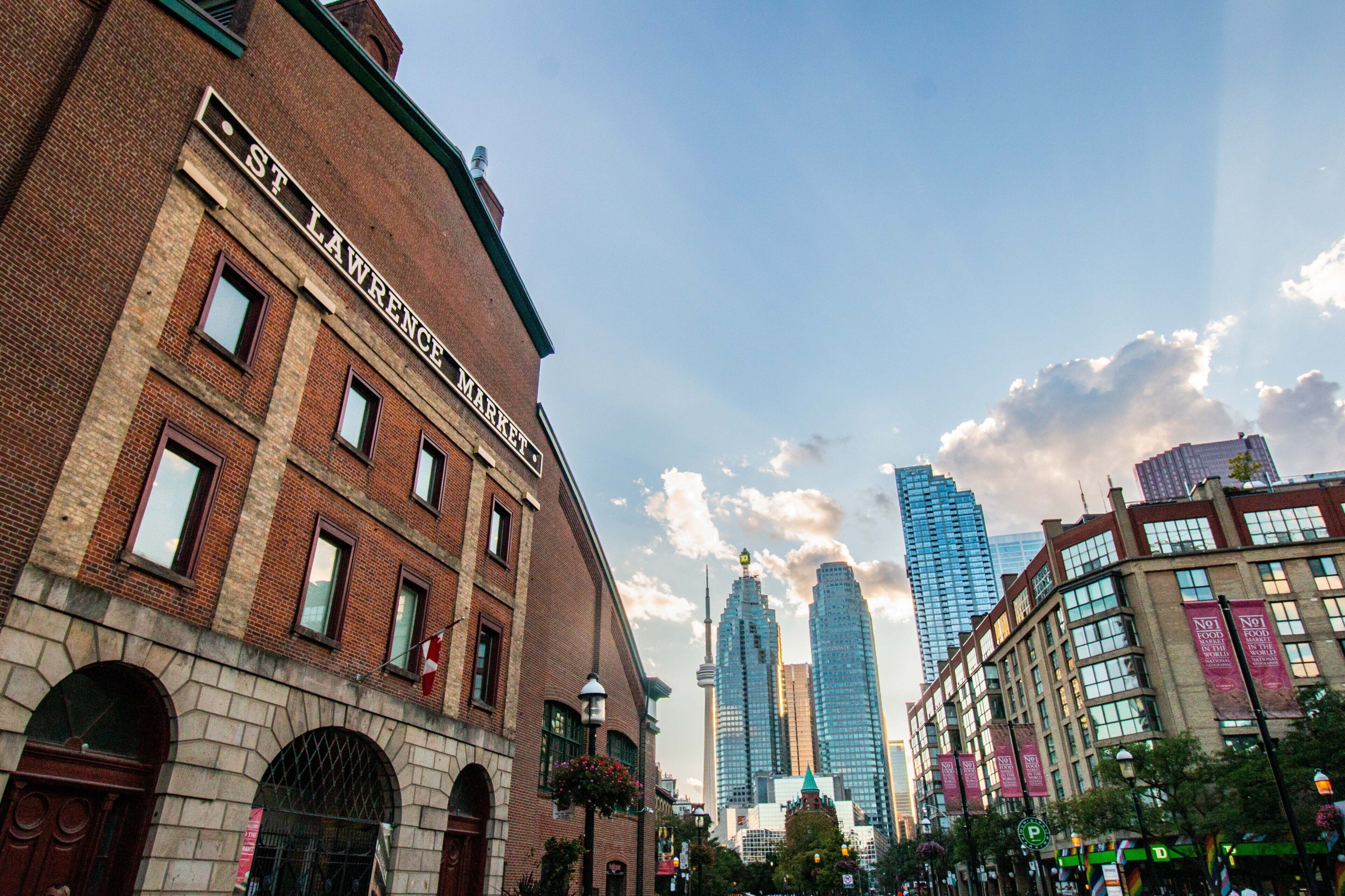 A historic building with a prominent sign reading 'ST LAWRENCE MARKET' and a modern skyscraper in the background.