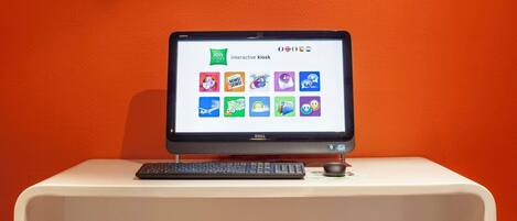 A Dell monitor on a white desk against an orange wall.