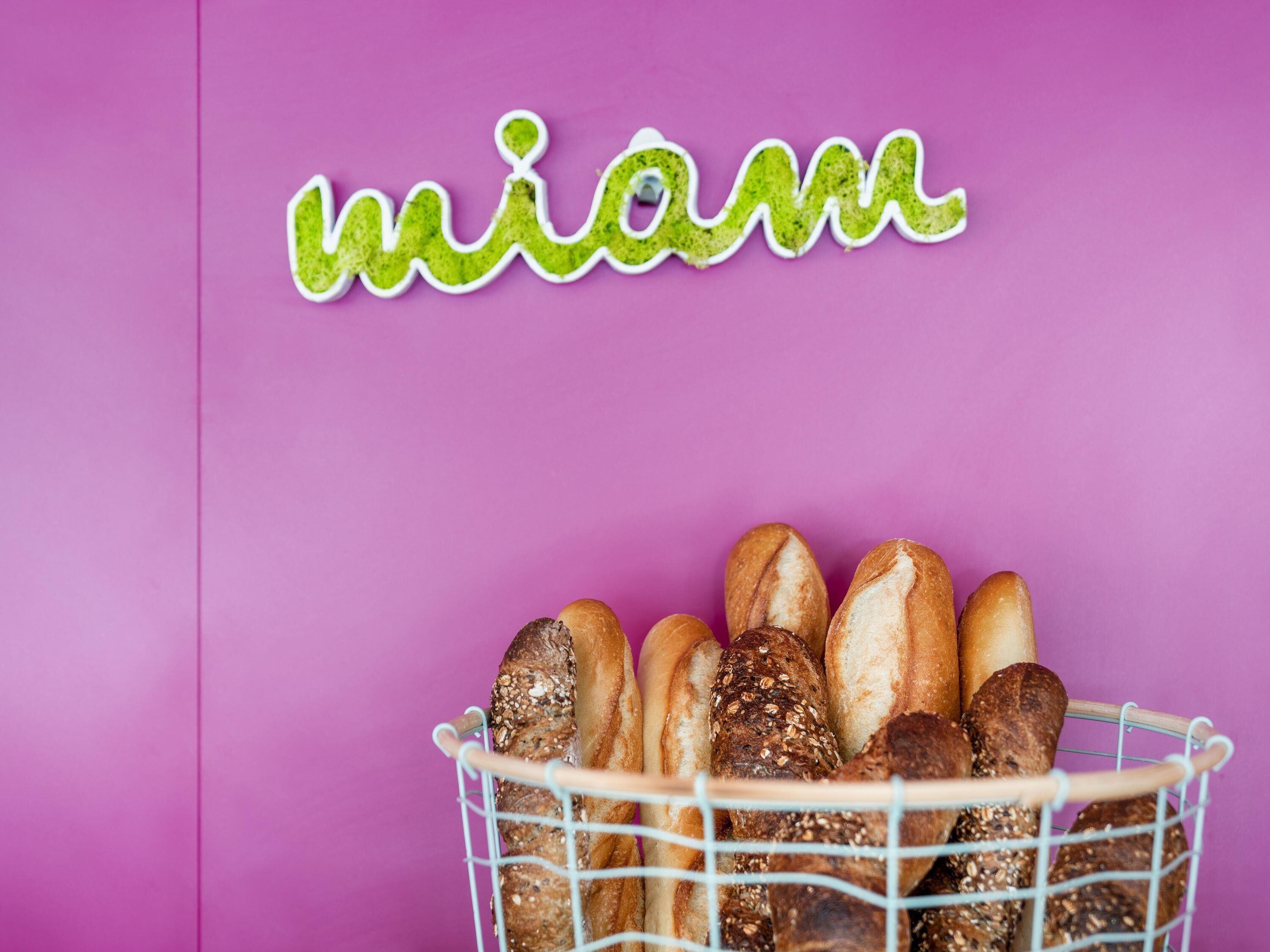 A basket of various breads on a pink background with the word 'miami' above.