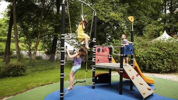 Kids can play on the climbing frame, slide, and rope bridge in this secure outdoor playground surrounded by trees.