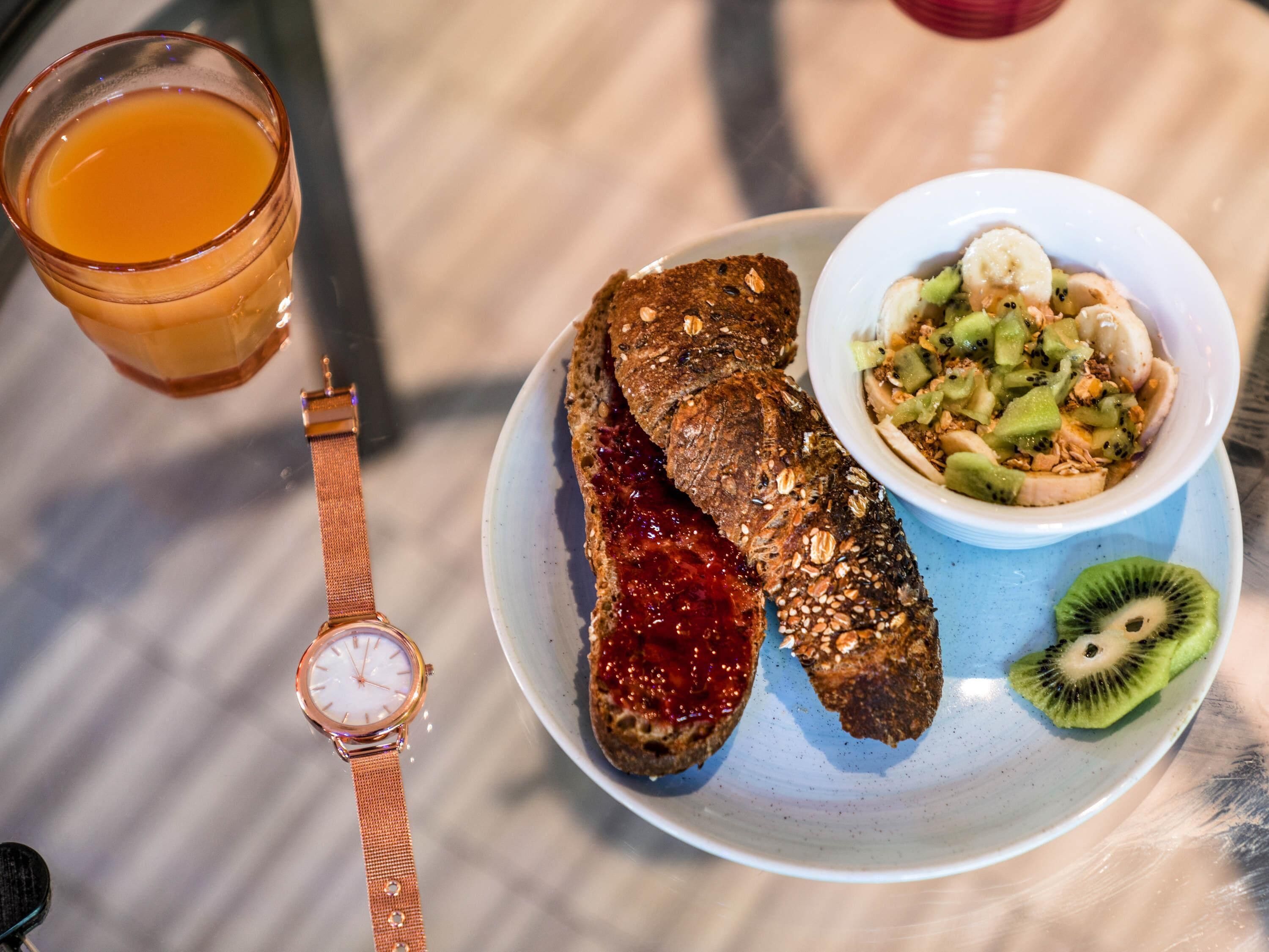 Un plato de desayuno con tostadas, un tazón de ensalada de frutas y un vaso de jugo de naranja.