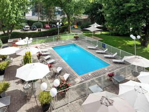 Relax by the pool surrounded by lush greenery and comfortable seating.
